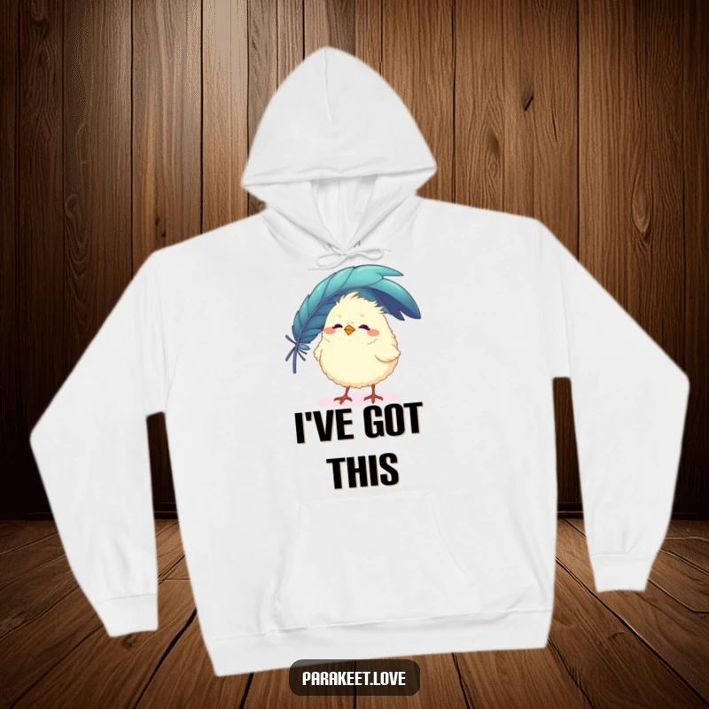 Funny hoodie featuring a fluffy, round bird trying to balance a large, colorful feather on its tiny beak. Cozy and humorous apparel.